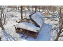A cozy single-story house with a brick porch and detached garage is surrounded by snow and bare trees in a peaceful setting at 210 S West St, Paragon, IN 46166