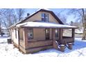 Cozy home featuring a welcoming covered porch with brick accents and tan siding, set against a snow-covered landscape at 210 S West St, Paragon, IN 46166
