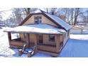 Charming single-story home with a brick-accented porch and detached garage, surrounded by a snow-covered yard at 210 S West St, Paragon, IN 46166