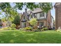 Attractive brick home with lush green lawn and mature trees, creating a welcoming ambiance at 219 Buckingham Dr, Indianapolis, IN 46208