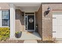 Inviting front entrance featuring a black door with a 'hello' wreath, potted flowers, and a brick facade at 5556 W Compass Pt, McCordsville, IN 46055