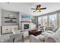 Cozy living room featuring a stone fireplace, a ceiling fan, and large windows offering ample natural light at 5556 W Compass Pt, McCordsville, IN 46055