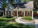 Charming brick home with a covered front porch and a curved concrete walkway surrounded by lush landscaping at 5860 Indianola Ave, Indianapolis, IN 46220