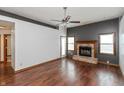 Open living room with hardwood floors, a ceiling fan, and a cozy brick fireplace at 10156 Park Royale Dr, Indianapolis, IN 46229