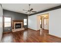 Open living room with hardwood floors, a ceiling fan, and a cozy brick fireplace at 10156 Park Royale Dr, Indianapolis, IN 46229