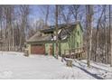 Side view of the two-story home featuring an attached garage and a quaint wooded lot at 1032 E Woodall Ct, Martinsville, IN 46151