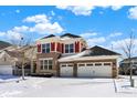 Charming two-story home featuring a brick facade, two-car garage and snowy front yard at 14905 W Blackwolf Run Dr, Carmel, IN 46033