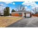 Well-maintained brick home with attached garage, mature trees, and long driveway at 1901 E Edgewood Ave, Indianapolis, IN 46227