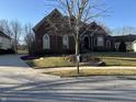 Charming brick home with a well-kept lawn and mature tree under a clear blue sky at 3841 Falls Cir, Carmel, IN 46033