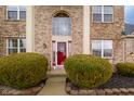 Close-up of the brick front entrance with red door, bushes, landscaping, and a large arched window at 538 Cyclamen Chase, Westfield, IN 46074