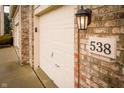Close-up of a three-car garage, address number, exterior brick, and an outdoor light fixture at 538 Cyclamen Chase, Westfield, IN 46074