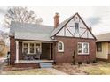 Quaint brick Tudor-style home featuring a cozy front porch and well-maintained exterior at 6189 Primrose Ave, Indianapolis, IN 46220