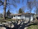 An exterior view of a single-story home featuring an attached garage, mature trees and yard with spotty lawn at 7406 E 33Rd St, Indianapolis, IN 46226