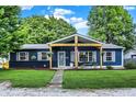 Charming navy blue home featuring a covered porch, manicured lawn, and blossoming hanging flower baskets at 790 N 14Th St, Noblesville, IN 46060
