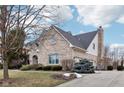 Side view of a brick house showcasing a black roof, landscaped yard, and spacious driveway at 9956 Hickory Ridge Dr, Zionsville, IN 46077