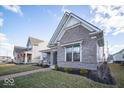 A quaint home with landscaped yard, brick pathway, and covered porch with seating for relaxing outdoors at 1225 Stonehaven Dr, Westfield, IN 46074