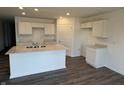 Bright kitchen featuring a large island with a double sink, white cabinets, and wood-look floors at 1414 Bluebonnet Pl, Shelbyville, IN 46176