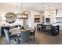 Elegant dining area featuring a round wood table, stylish chairs, and a modern chandelier with an island and gourmet kitchen at 16822 Imperial Ct, Fishers, IN 46040