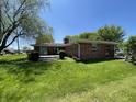Spacious backyard with lush green grass, mature landscaping, and a brick home with an outdoor patio at 2130 Theobald St, Shelbyville, IN 46176
