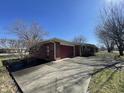 View of a brick house with a garage, showcasing the spacious driveway and mature trees at 2130 Theobald St, Shelbyville, IN 46176