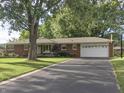 Lovely brick home featuring an attached garage, front porch swing, and an expansive driveway at 2210 Brewer Dr, Indianapolis, IN 46227