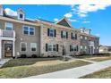 Beautiful townhome exterior featuring brick, dormer windows, well-kept landscaping, and blue skies at 2792 Maricopa Blvd, Whitestown, IN 46075
