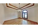 Bright dining room with a stylish chandelier, tray ceiling and a large arched window at 4285 S Woodbridge Ln, New Palestine, IN 46163