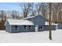 View of the charming blue home featuring a metal roof and snowy front yard at 6205 Beech Grove Rd, Martinsville, IN 46151