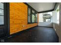 Spacious front porch featuring stained wood paneling, black trim, and painted concrete flooring at 633 E 32Nd St, Indianapolis, IN 46205