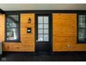 Inviting front porch featuring wood paneling, black trim, and a traditional black front door at 633 E 32Nd St, Indianapolis, IN 46205