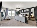 Elegant main bedroom featuring a decorative chandelier, dark accent wall and a cozy seating area at 8148 Ebaugh Dr, Camby, IN 46113