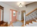 Inviting foyer with a light pink door, staircase with wrought iron spindles, and hardwood flooring at 12107 Castle Row Overlook, Carmel, IN 46033