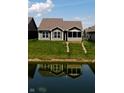 Back of a home with a backyard pond, light gray siding, and large windows for natural light at 1223 Blackthorne S Trl, Plainfield, IN 46168