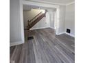 Sunlit living room featuring wood-look flooring, staircase, and doorway to adjoining room at 123 S Butler Ave, Indianapolis, IN 46219