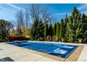 A large, in-ground swimming pool is surrounded by tall trees and lush greenery and has lounging chairs nearby at 1813 Milford St, Carmel, IN 46032