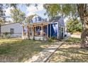 Side view of a blue home with a sidewalk leading up to a cozy front porch, surrounded by lush greenery at 2224 E Pleasant Run Parkway North Dr, Indianapolis, IN 46203