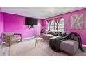 Bright living room featuring sleek wood-look floors, eye-catching fuchsia walls, and modern furniture at 3332 Ashway Dr, Indianapolis, IN 46224