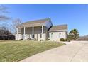 A gray brick home with a manicured lawn and inviting covered entrance with multiple seating areas at 3332 W Raven Field Blvd, Greenfield, IN 46140