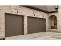 Attached two car garage with raised panel doors and charming sconce lighting near the arched entry at 3588 Marketplace Ct, Zionsville, IN 46077