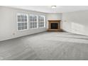 Spacious living room with plush carpeting, a cozy fireplace, and bright natural light from large windows at 4140 Congaree Dr, Indianapolis, IN 46235