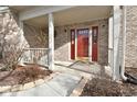 Charming covered front porch with a vibrant red door, brick columns, and manicured landscaping at 7044 Bel Moore Cir, Indianapolis, IN 46259