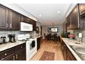 Well-lit kitchen featuring dark wood cabinetry, white appliances, modern countertops, and seamless flow into the dining area at 2456 N Willow Way, Indianapolis, IN 46268