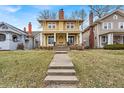 Charming two-story home with tan siding, a red roof, a welcoming front porch, and a well-manicured front lawn at 3416 Guilford Ave, Indianapolis, IN 46205