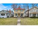 Two-story home with a red roof, tan siding, a welcoming front porch, and a well-manicured front lawn at 3416 Guilford Ave, Indianapolis, IN 46205