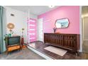 Colorful entryway featuring a pink accent wall, mid-century furnishings, and a unique front door at 6015 Pine Hill Dr, Indianapolis, IN 46235