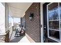 Inviting front porch with rocking chairs, brick accents, and a secure front door at 13702 Beam Ridge Dr, Fishers, IN 46055
