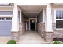 Covered front porch with stone accents and a black front door at 16401 Brigham Ln, Westfield, IN 46074