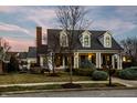 Charming two story home with a covered front porch and mature landscaping at dusk at 2235 Shaftesbury Rd, Carmel, IN 46032