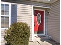 Close-up of the front door with an oval window, complemented by gray siding and a neatly trimmed shrub at 5620 E Sunshine Ct, Mooresville, IN 46158