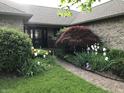 Charming home entrance featuring a brick pathway, colorful flowerbeds, and a beautifully landscaped front yard at 8329 Hill Gail Dr, Indianapolis, IN 46217